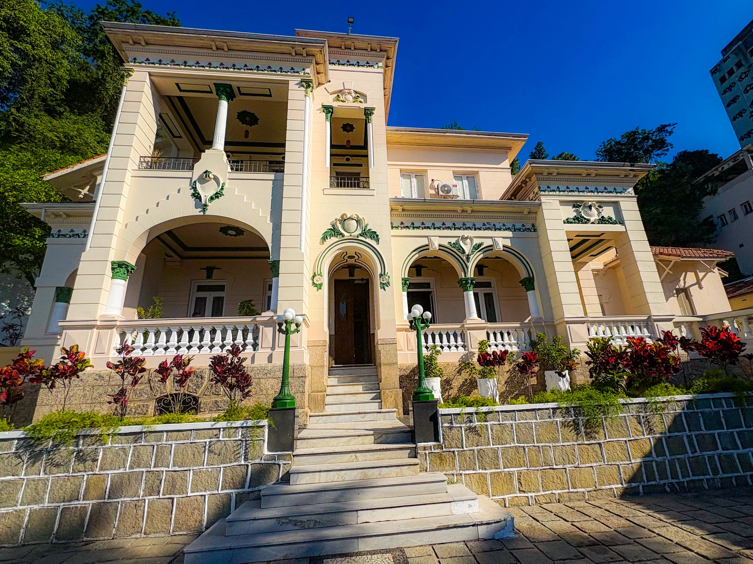 Fachada do casarão eclético da Casa das Luzes, com colunas, arcos e ornamentos verdes, ao sol da manhã.